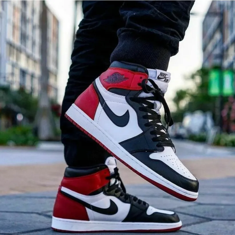 Air Jordan 1 cano alto preto, branco e vermelho no pé, na rua