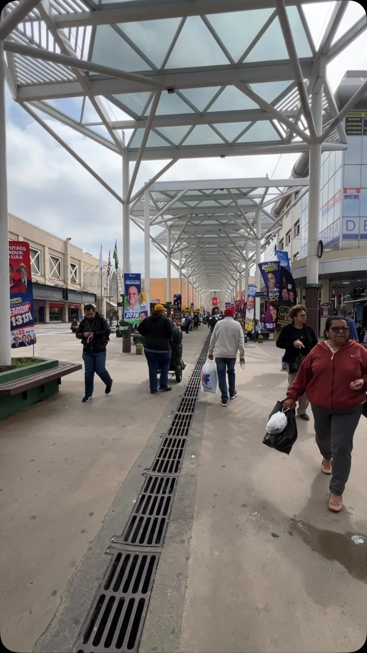 O calçadão coberto da Rua Antônio Agu, em Osasco, com a estrutura de aço e vidro e gente passando